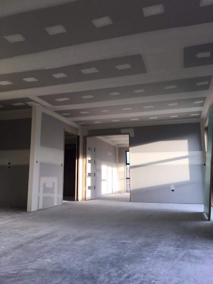 Feathered plaster repair on an unpainted wall viewed under side lighting